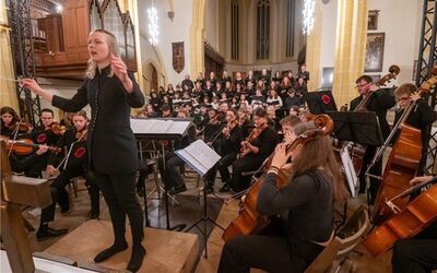 Im Altarraum der Stiftskirche Herrenberg. Die Dirigentin steht zum Publikum gedreht. Im Hintergrund ist das Orchester und der Chor.
