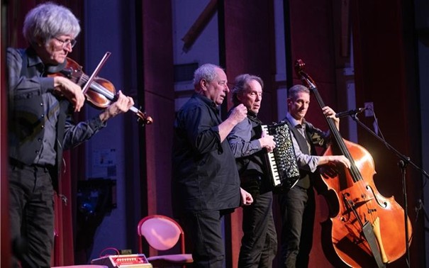 Auf der Bühne der Alten Turnhalle musiziert das Ensemble JONTEF. Vier Männer mit Violine, Gesang, Akkordeon und Kontrabass.