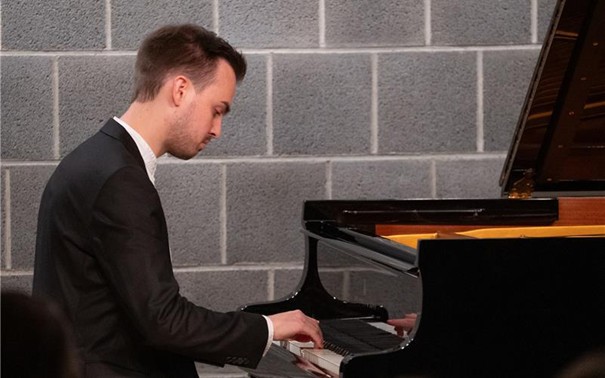 Der Pianist Lukas Saalfrank sitzt am Flügel. Sein Ausdruck ist konzentriert und andächtig.